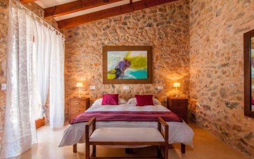 a bedroom with a bed and a stone wall at Es Romagueral in Artá