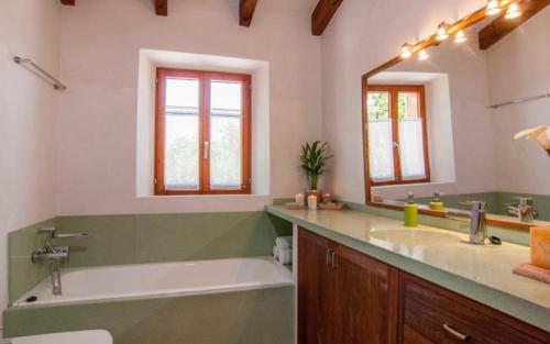 a bathroom with a tub and a sink and a mirror at Es Romagueral in Artá