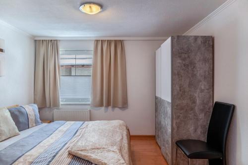 a bedroom with a bed and a chair and a window at Apart Bergtraum Ried - Typ 2 in Ried im Oberinntal