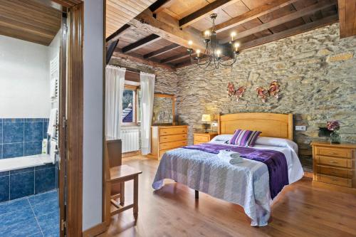 a bedroom with a bed and a stone wall at La Posada Del Chano in Cerecedo de Besullo