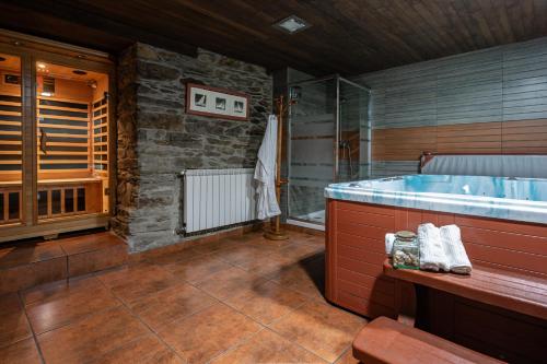 a bathroom with a tub and a stone wall at La Posada Del Chano in Cerecedo de Besullo