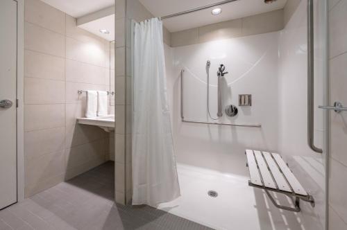 a white bathroom with a shower and a bench at Norwood Hotel in Winnipeg