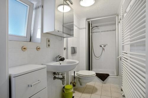 a white bathroom with a sink and a toilet at Bäckerhus - Ferienwohnung 2 in Wiek auf Rügen