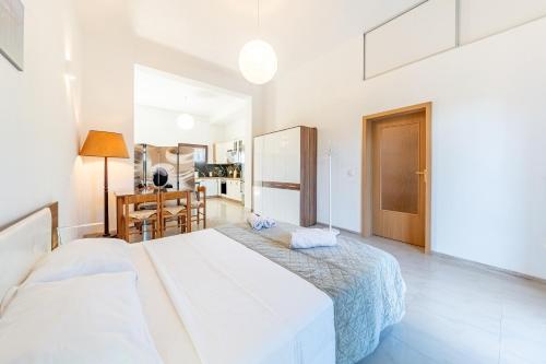 a white bedroom with two beds and a kitchen at Melissa apartments in Halikounas
