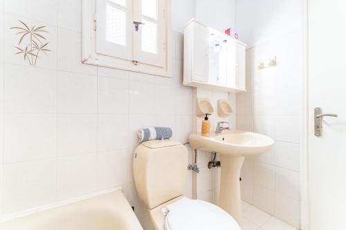 a white bathroom with a toilet and a sink at Olivea Studio 2 in Acharavi