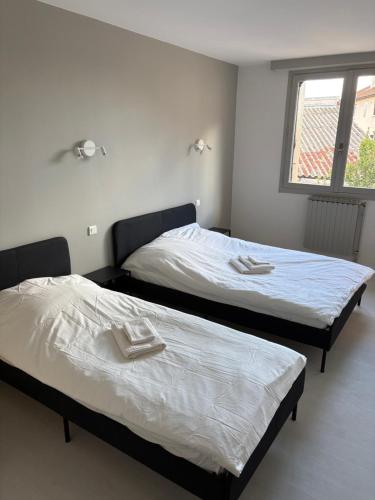 two twin beds in a room with a window at Hôtel café des cours in Cébazat