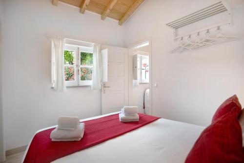 a white bedroom with a bed with two towels on it at Páteo da Várzea 2 in Colares