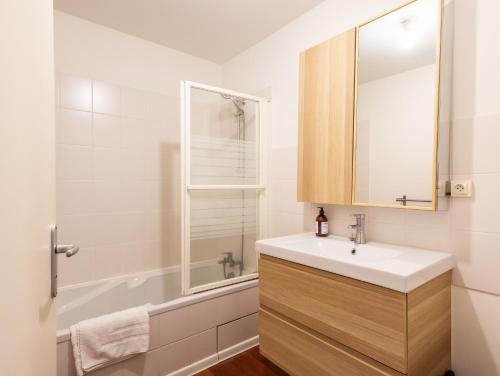 a bathroom with a sink and a mirror and a tub at Pieds Dans L'eau Madame est Servie in Trébeurden