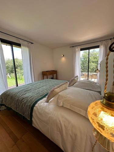 a bedroom with a bed with a table and windows at Chambres d'hote Bergerie A Maredda in Murato