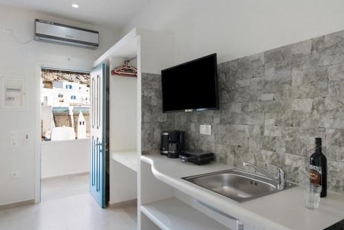 a kitchen with a sink and a tv on the wall at Politimis Studio N1 in Amorgos