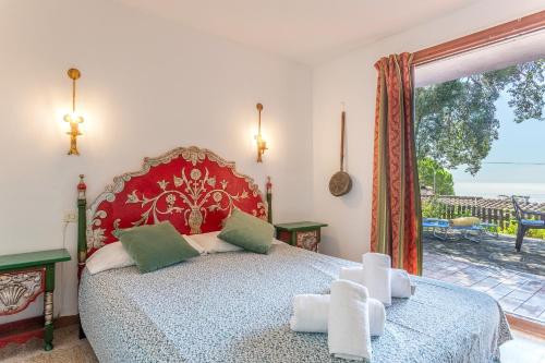 a bedroom with a bed with a red headboard and a window at Casa Yves in Tossa de Mar