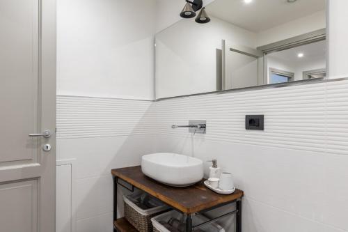 a white bathroom with a sink and a mirror at Casa Masoni in Colle di Val d'Elsa