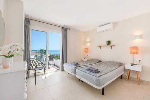 a bedroom with a bed and a balcony with the ocean at Rocas del Mar in Mijas