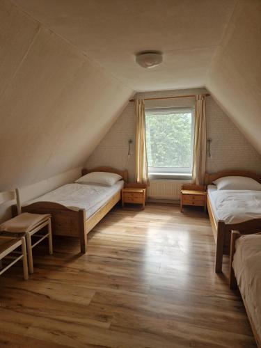 a attic room with two beds and a window at Ferienhof Rosenwarft in Pellworm