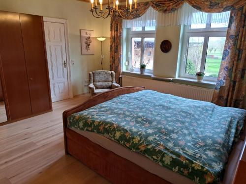 a bedroom with a bed and a chair and windows at Hof Schumacher in Gumtow