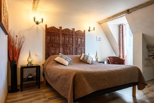 a bedroom with a large bed with a wooden headboard at Demeure D'antan - Chambres d'hôtes in Beblenheim