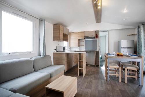 a living room and kitchen with a couch and a table at Bungalow T3 I I -15 Min From Nazaré in Pataias