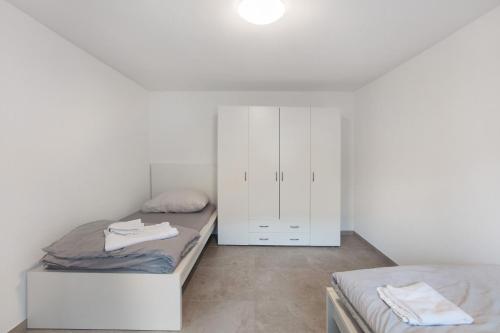 a bedroom with two beds and a white cabinet at Ferienapartments Ariana in Bad Säckingen