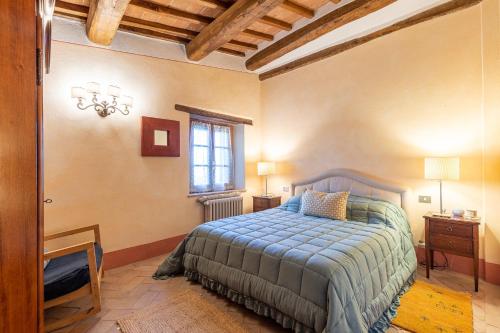 a bedroom with a bed with a blue comforter and a window at La Terrazza, Cetona, Toscana in Cetona