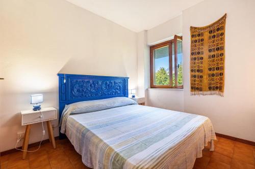 a bedroom with a blue bed and a window at Villa Franca San Zeno in San Zeno di Montagna