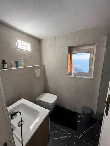 a bathroom with a toilet and a sink and a window at Casa Mark in Forza dʼAgro