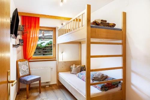 a small room with a bunk bed and a ladder at Hotel Sonnblick - Wohnung Klaus in Kartitsch