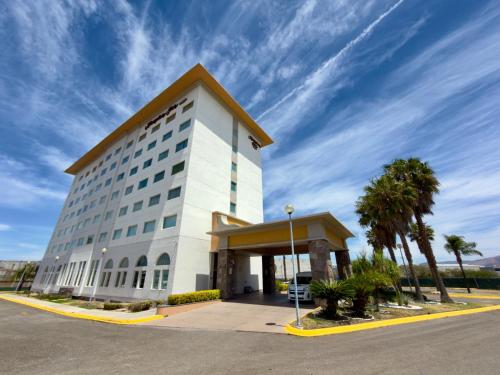 a large white building with palm trees in front of it at Hampton Inn by Hilton Silao-Aeropuerto, Mexico in Silao