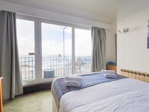 a bedroom with a bed and a large window at De L'Etang in Saint Helier Jersey