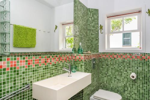 a green tiled bathroom with a sink and a toilet at Casa Ullastre de Fornells in Fornells