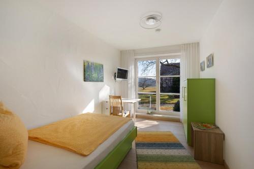 a bedroom with a bed and a desk and a window at Birkethof Gartenblick in Grimoldsried