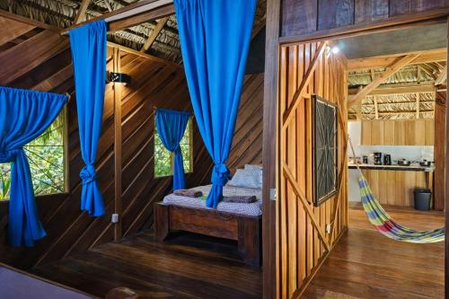 a room with blue curtains and a bed in a tree house at Wildlife Lodge Cahuita in Cahuita