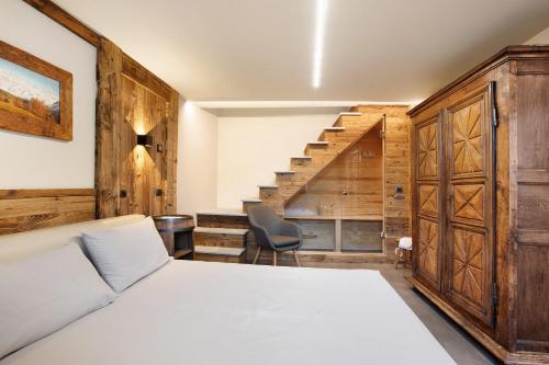 a bedroom with a white bed and a staircase at Alpine A-S in Aymavilles