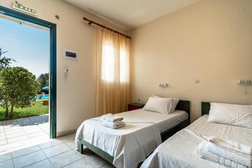 two beds in a room with a sliding glass door at Anemona studio B in Kefallonia