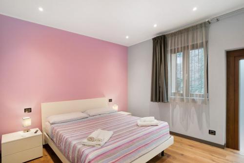 a bedroom with pink walls and a bed with two towels at Agriturismo il Borgo - Lavanda in Villanova dʼAlbenga