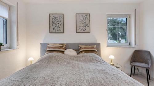 a bedroom with a large bed with two windows at Ferienwohnung Heidegarten in Radolfzell am Bodensee