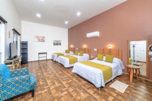 ein Hotelzimmer mit zwei Betten und einem Stuhl in der Unterkunft Hotel Boutique Las Campanas in Tlaxcala de Xicohténcatl