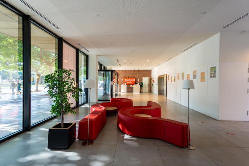 a lobby with red furniture and a large window at easyHotel Barcelona Fira in Hospitalet de Llobregat