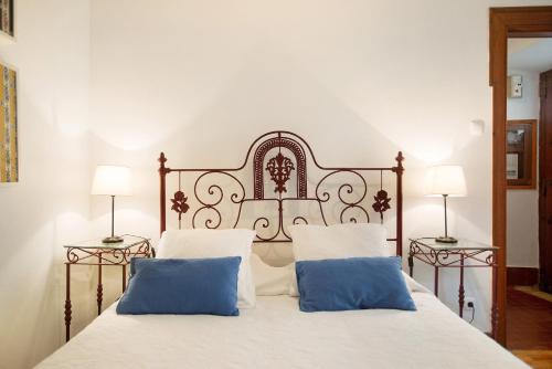 a white bed with two blue pillows on it at São Martinho All The Best in São Martinho do Porto