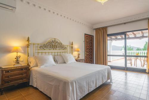 a bedroom with a white bed and a large window at Can Joan Vich I in Santa Eularia des Riu