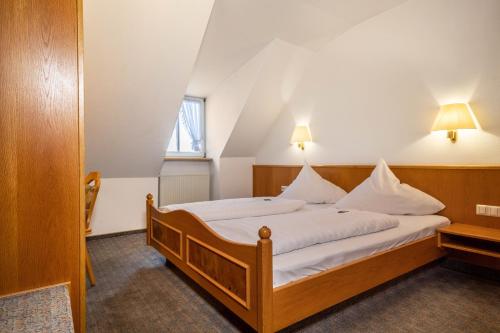 a bedroom with a bed with white sheets at Gasthof Adler in Ebenweiler