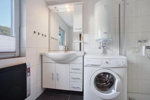 a bathroom with a washing machine and a sink at Ferienhaus Am Darß - Leuchtturm in Pruchten