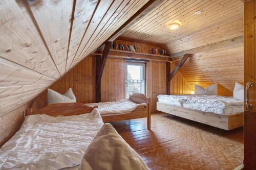 a bedroom with two beds in a room with wooden walls at Ferienhaus Am Darß - Leuchtturm in Pruchten