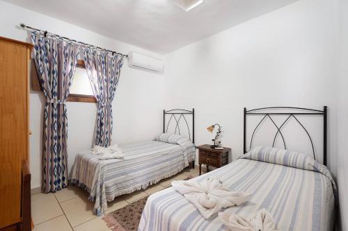 a bedroom with two beds and a table and a window at Casa Rural Medina 1 in Agulo