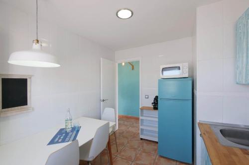 a kitchen with a blue refrigerator and a table at Posidonia in Portocolom