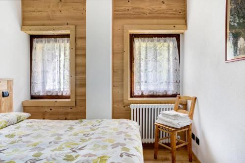 a bedroom with a bed and two windows at Alta Valle Maira B in Acceglio