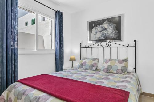 a bedroom with a bed with a red blanket on it at Coqueto y tranquilo Apartamento in Puerto del Carmen