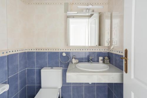 a blue and white bathroom with a toilet and a sink at Keops in Oliva