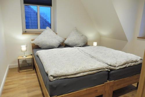 a bedroom with a bed with two pillows and a window at Dat rode Huus in Oesterwurth