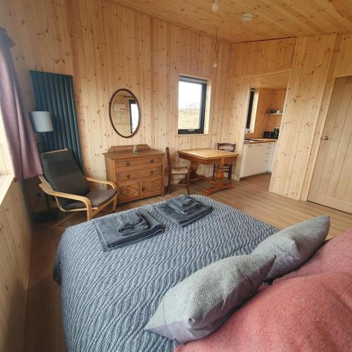 a bedroom with a bed and a chair and a table at The Other Wee Red Cabin in Dunvegan