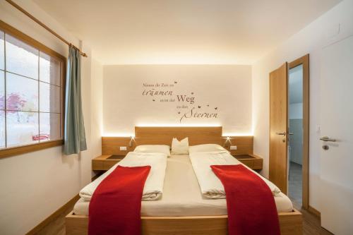 a bedroom with a bed with two red pillows on it at Schnitzer Ferienwohnung Anemone in Rablà